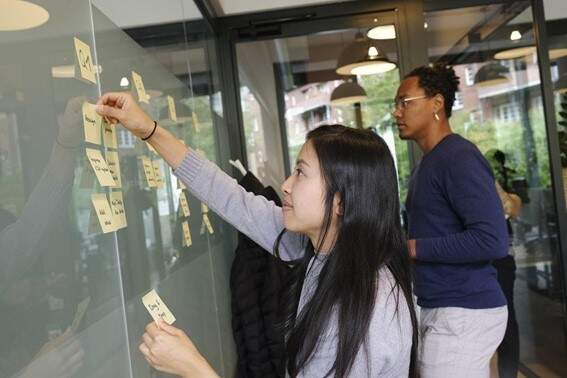 Na foto, temos uma mulher montando um quadro Kanban